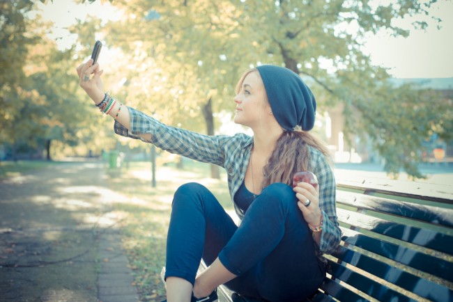 beautiful young blonde hipster stylish woman selfie in the park