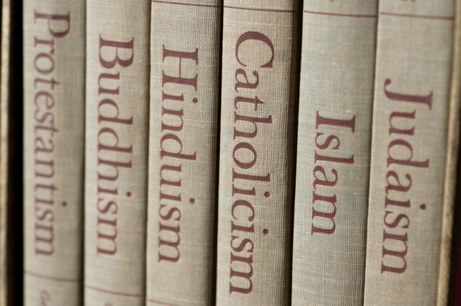Book spines listing major world religions – Judaism, Islam, Catholicism, Hinduism, Buddhism and Protestantism. The focus is on the word, Catholicism