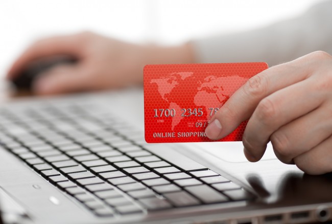 Man holding credit card in hand and entering security code using laptop keyboard class="wp-image-229179" 
