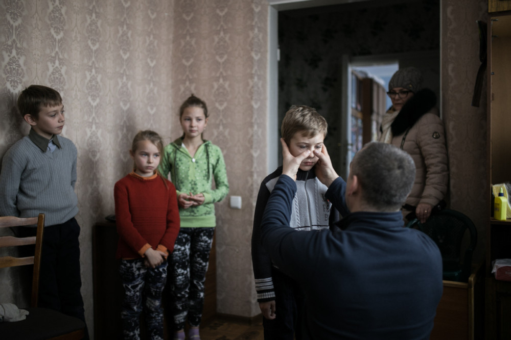 Zdjęcie pojedyncze - III miejsce w kategorii ŻYCIE CODZIENNE. Fot. Marta Rybicka, Naddniestrzańska Republika Mołdawska, Słoboda Raszkowska. Chłopiec z polskiej rodziny mieszkającej w tej republice właśnie miał wypadek. Z grupą dzieci jechał na zajęcia muzyczne, gdy nagle samochód wpadł w poślizg i zderzył się z drugim jadącym z naprzeciwka. Na szczęście dzieci doznały tylko drobnych obrażeń. Na zdjęciu polski ratownik medyczny, który przyjechał w ramach Charytatywnej Akcji Mikołajkowej, ogląda i pociesza chłopca. 15 grudnia 2018. class="wp-image-939419" 