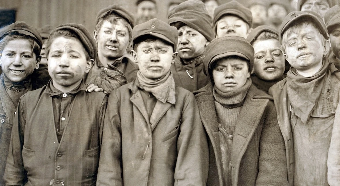 Dzieci-robotnicy z kopalni węgla Pennsylvania Coal sportretowani przez fotografa Lewisa Hine'a w 1911 roku. Chłopcy są pokryci węglowym pyłem, bo pracowali oddzielając młotami łupki od wydobytego węgla. Fot. Lewis Hine / Shutterstock / Everett Collection