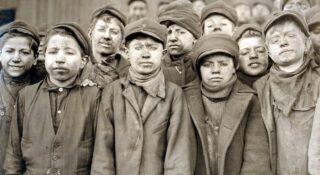 Dzieci-robotnicy z kopalni węgla Pennsylvania Coal sportretowani przez fotografa Lewisa Hine'a w 1911 roku. Chłopcy są pokryci węglowym pyłem, bo pracowali oddzielając młotami łupki od wydobytego węgla. Fot. Lewis Hine / Shutterstock / Everett Collection