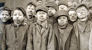 Dzieci-robotnicy z kopalni węgla Pennsylvania Coal sportretowani przez fotografa Lewisa Hine'a w 1911 roku. Chłopcy są pokryci węglowym pyłem, bo pracowali oddzielając młotami łupki od wydobytego węgla. Fot. Lewis Hine / Shutterstock / Everett Collection