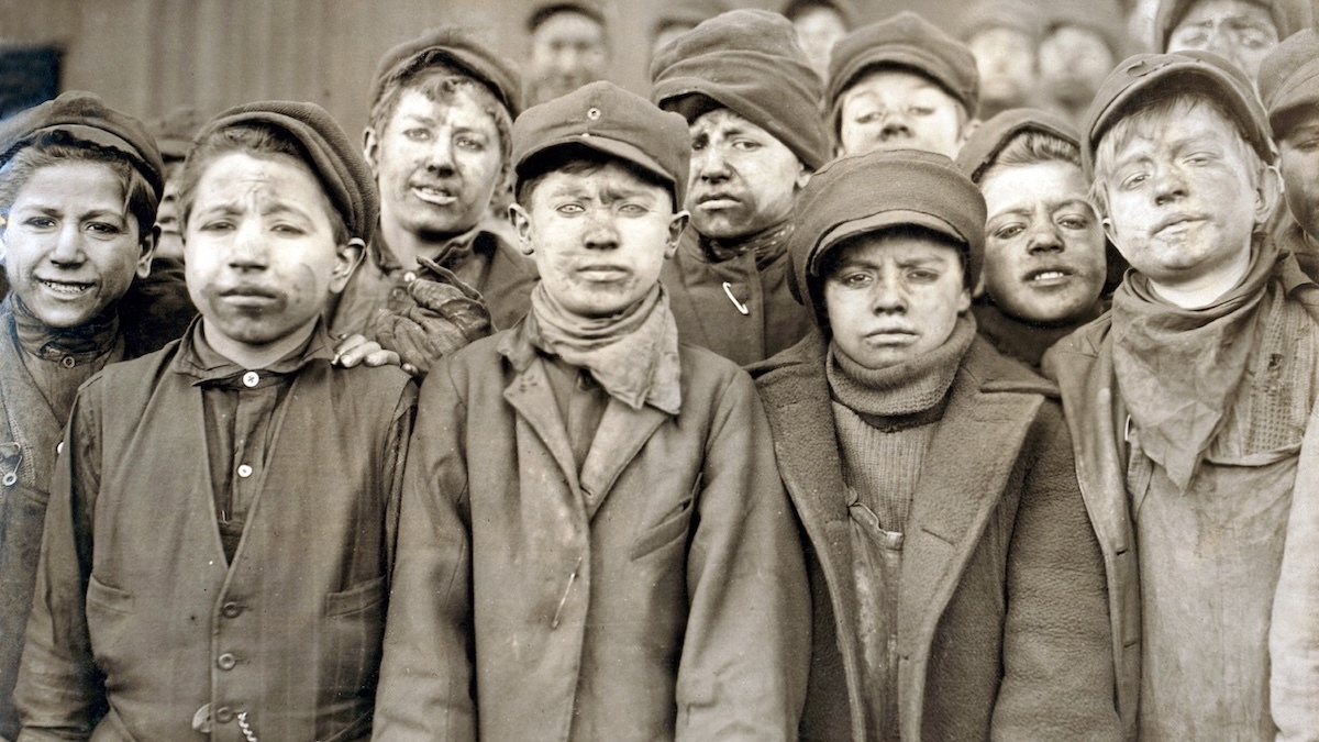 Dzieci-robotnicy z kopalni węgla Pennsylvania Coal sportretowani przez fotografa Lewisa Hine'a w 1911 roku. Chłopcy są pokryci węglowym pyłem, bo pracowali oddzielając młotami łupki od wydobytego węgla. Fot. Lewis Hine / Shutterstock / Everett Collection