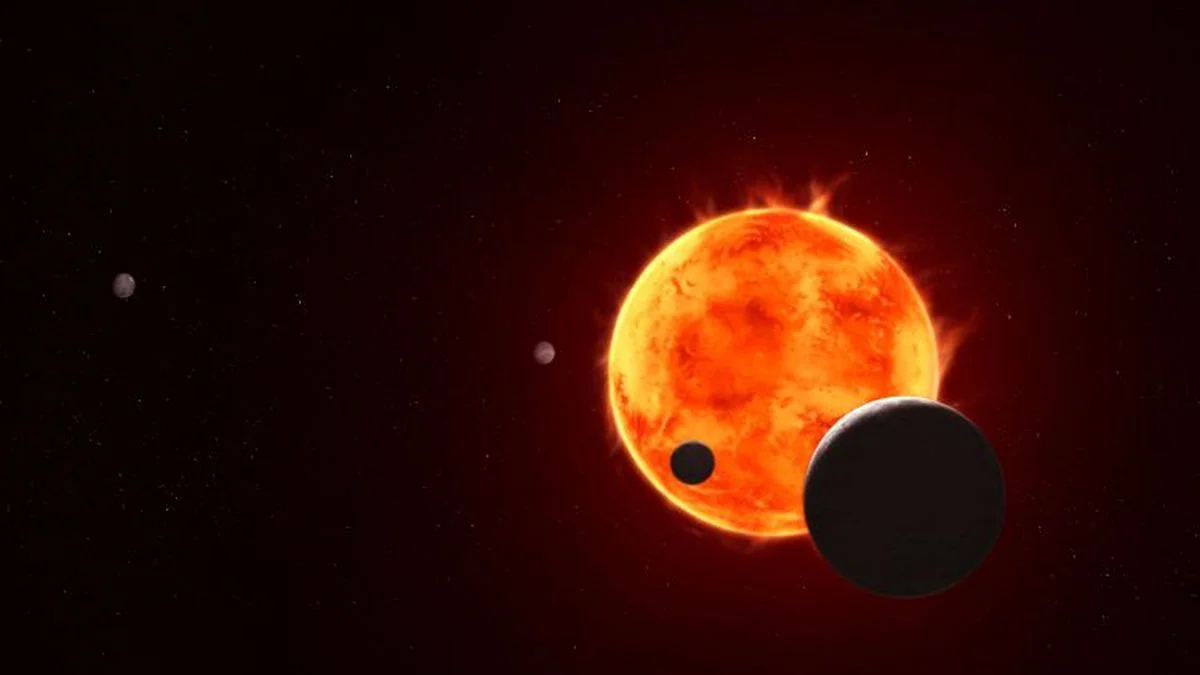 Egzoplaneta TRAPPIST-1 e, wielkości Ziemi, przedstawiona w prawym dolnym rogu, jest widoczna przechodząca przed swoją gwiazdą macierzystą na tej artystycznej wizualizacji układu TRAPPIST-1. Naukowcy nazywają to zjawisko tranzytem, ponieważ pozwala ono na zebranie cennych danych podczas przejścia egzoplanety między gwiazdą a teleskopem, a światło gwiazdy oświetla atmosferę (o ile taka istnieje). Kosmiczny Teleskop Jamesa Webba NASA przeprowadził wstępne obserwacje planet b, c, d i e podczas ich tranzytów, a kolejne obserwacje planety e są w toku. Chociaż częste rozbłyski gwiazdy utrudniają wykrycie atmosfery, każdy tranzyt dostarcza naukowcom coraz więcej informacji, które pozwalają im uzyskać pełniejszy obraz tych odległych światów.